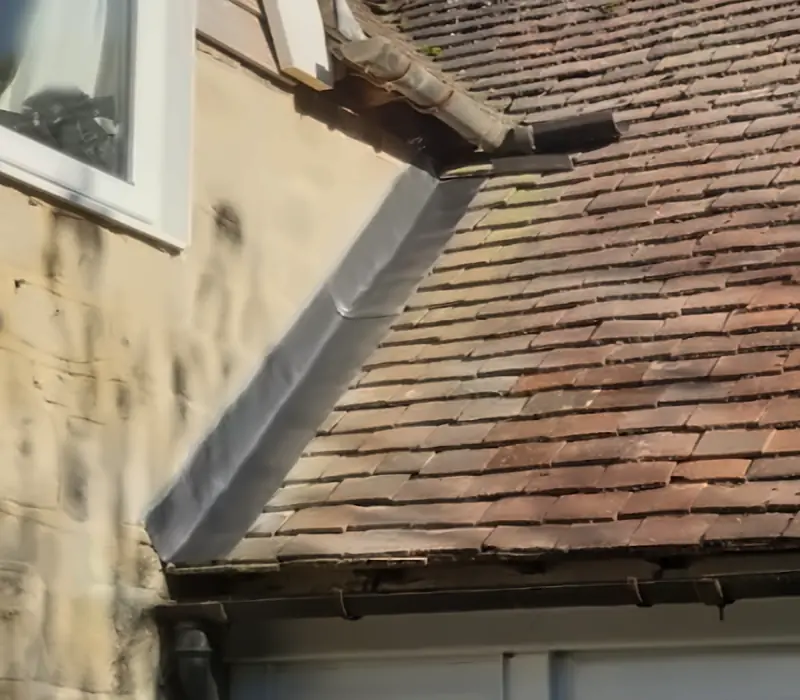 Lead flashing where a clay tile roof meets a wall